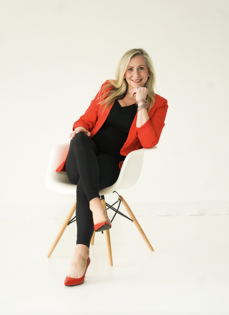 woman in red jacket with legs crossed sitting in chair